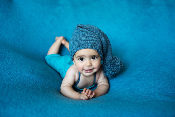 Söpö vastasyntynyt vauva sinisessä hatussa. Onnellinen vauva sinisellä taustalla. Lähikuva muotokuva vastasyntyneen vauvan. Vauvan tavaroiden pakkausmalli. Lastenhuone. Lääketieteellinen ja terve käsite. Joulu. Uusi vuosi - Valokuva, kuva
