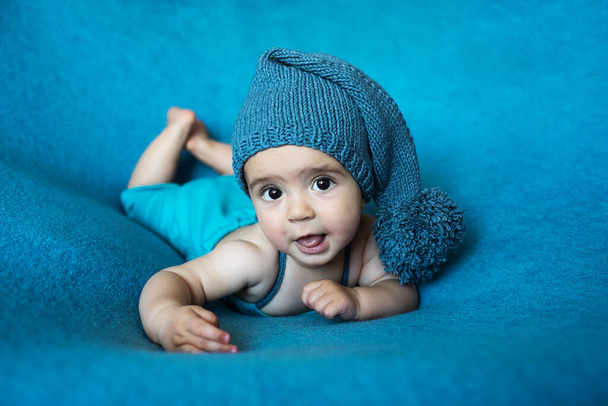 Söpö vastasyntynyt vauva sinisessä hatussa. Onnellinen vauva sinisellä taustalla. Lähikuva muotokuva vastasyntyneen vauvan. Vauvan tavaroiden pakkausmalli. Lastenhuone. Lääketieteellinen ja terve käsite. Joulu. Uusi vuosi - Valokuva, kuva