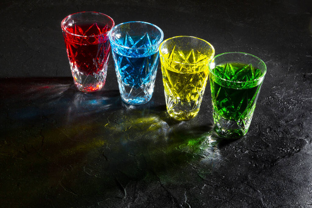 Gafas de chupito multicolores con alcohol fuerte sobre fondo oscuro - Foto, imagen