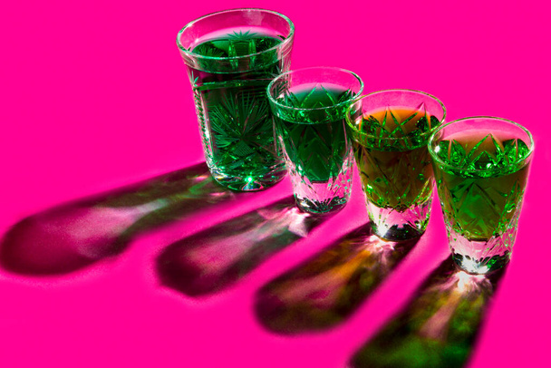 アルコールが強い。ピンクを背景にabsintheとショットグラス - 写真・画像