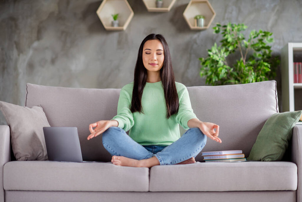 Full size photo of focused calm korean girl sit couch legs crossed folded barefoot meditate work study break pause in house indoors - Фото, изображение