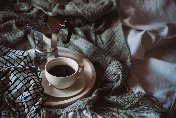 Cup of coffee on tray in cozy winter bad with wool blanket - Photo, Image