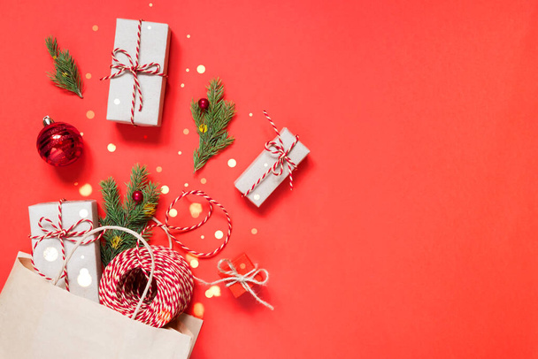 Paper bag with Christmas gifts and decorations on a red background with copy space - Foto, imagen
