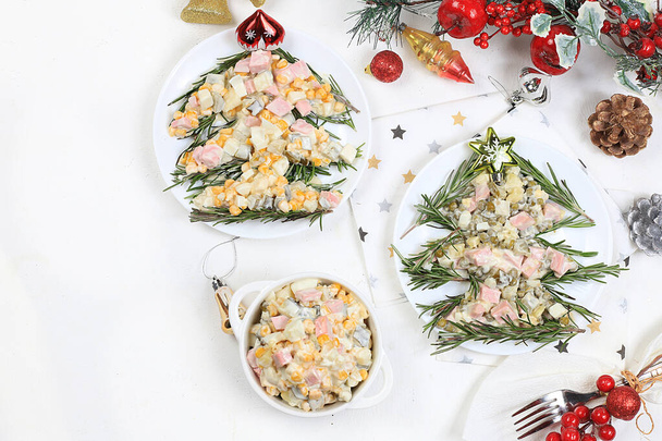 Christmas new year food, traditional festive olivier salad with fir branches and cones and decorations on a light table, idea for food design, place for recipe, flat lay, selective focus - Valokuva, kuva