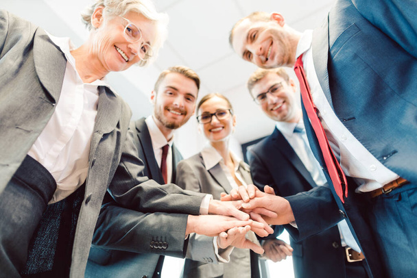 Business-Team stapelt Hände und blickt in die Kamera - Foto, Bild