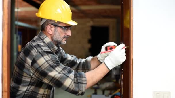 Carpenter worker at work with measuring tape and pencil, repairs and installs the door frame of a room. Construction industry. Carpentry. Footage. - Footage, Video