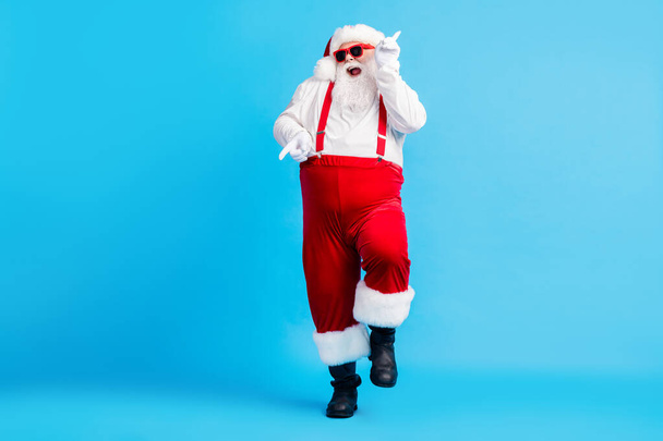 Full size photo of funky fat crazy santa claus with big abdomen beard dance x-mas christmas holly party club wear suspenders overalls sunglass boots isolated blue color background - Fotó, kép