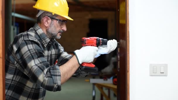 Carpenter worker at work with an electric screwdriver, repairs and installs the door frame of a room. Construction industry. Carpentry. Footage. - Footage, Video