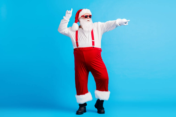 Full size photo of cool hipster santa claus with big belly dance x-mas christmas magic discotheque wear suspenders cap sunglass isolated over blue color background - Fotó, kép