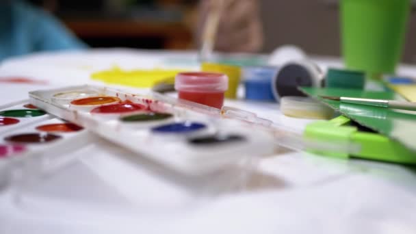 Kid Hand Draws With a Brush Against the Backdrop of a Creative Mess. Aquarela - Filmagem, Vídeo
