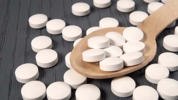 Pilules blanches d'additifs alimentaires dans une cuillère en bois sur une surface en bois grunge fermer - Séquence, vidéo