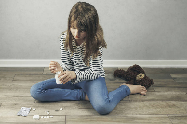 Психологічне, психічне здоров'я. Дівчинка-підліток сидить на підлозі і п'є таблетки на руці. Допомога підліткам
. - Фото, зображення