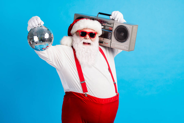Photo of old man grey beard raise hands hold vintage glowing ball boom box wear santa claus x-mas costume suspenders sunglass white shirt headwear gloves isolated blue color background - Фото, изображение