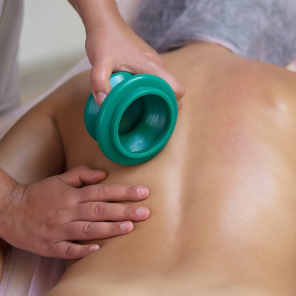 Massagetherapeut masseren jonge vrouw. Vacuümmassage - Foto, afbeelding