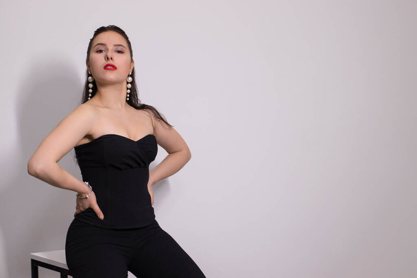 emotional portrait of sexy attractive brunette in black costume with white pearl earrings on white background - Φωτογραφία, εικόνα