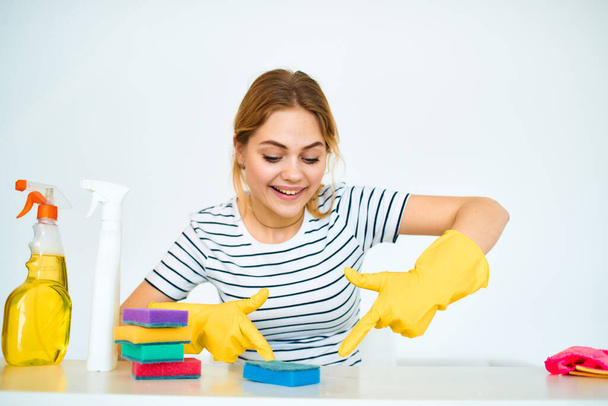 Lastik eldivenli temizlikçi kadın masa temizleme aletlerinde oturuyor. - Fotoğraf, Görsel