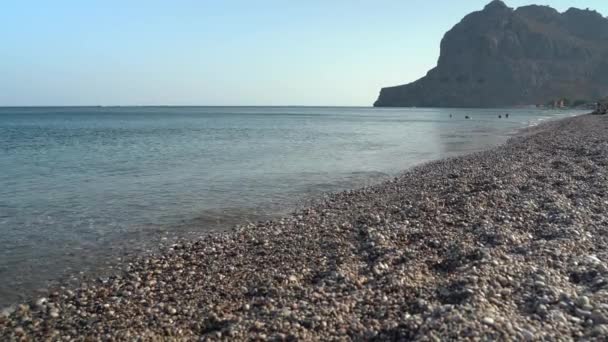 Rodi, Grecia: Colpo di spiaggia / lungomare con pietre contro le onde durante il giorno in estate. - Filmati, video