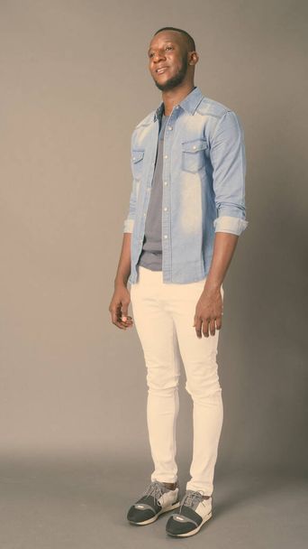 Jovem e bonito homem africano com cabelo curto contra fundo cinza - Foto, Imagem
