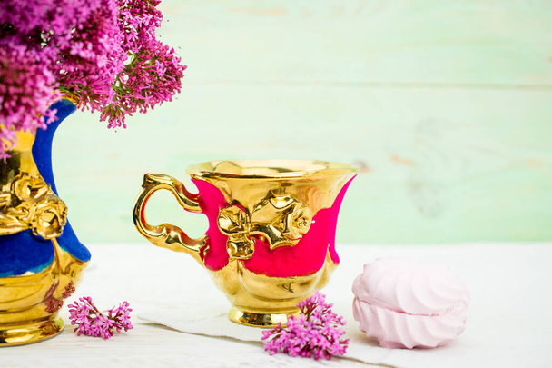 Fondo blanco con rama lila en el jarrón y copa dorada - Foto, Imagen