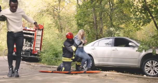 Firemen helping multiracial couple after car crash - Footage, Video