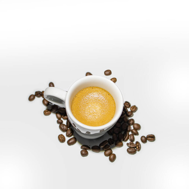 volle koffie kopje op schone witte achtergrond met bonen - Foto, afbeelding