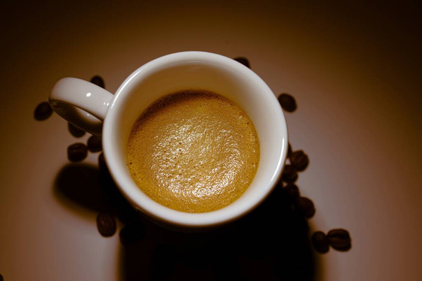 чашка кофе на коричневом фоне и бобы - Фото, изображение