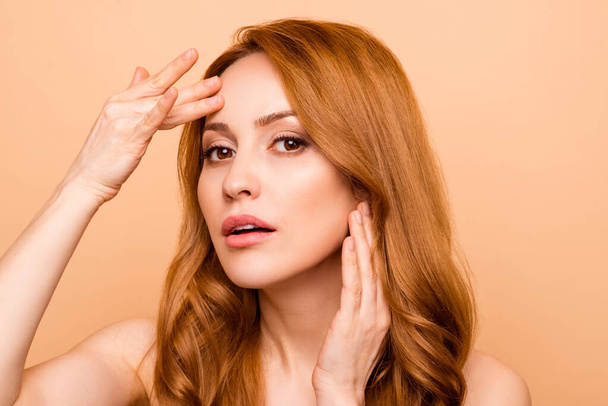 Close-up portrait of her she nice-looking attractive lovely nude naked shine worried wavy-haired lady touching forehead problem place laser therapy treatment isolated over beige pastel background - 写真・画像