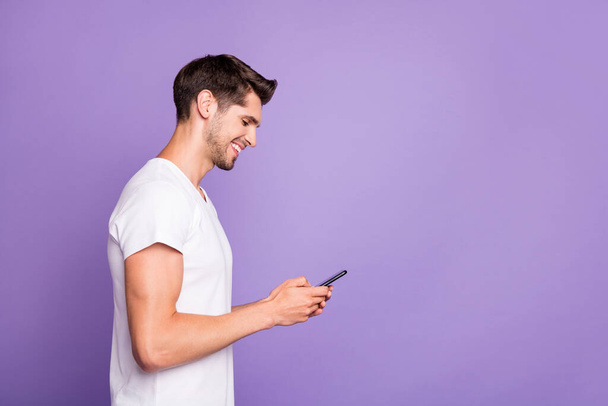 Profile side view portrait of his he nice attractive cheerful cheery focused guy using cell chatting browsing web isolated over bright vivid shine vibrant violet lilac purple color background - Foto, Imagem