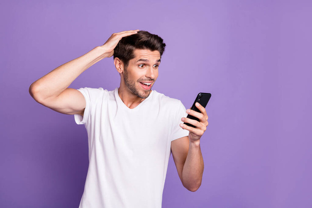 Portrait of his he nice attractive cheerful cheery glad stunned amazed guy using cell app 5g reading browsing good news isolated over bright vivid shine vibrant violet lilac purple color background - Zdjęcie, obraz