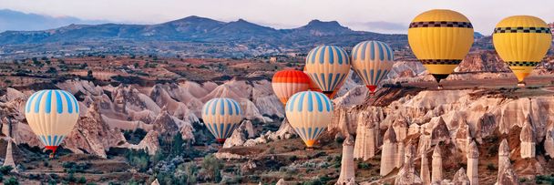Wide landscape with colorful hot air balloons flying over mountain landscape in Cappadocia, Goreme National Park ,Turkey. - Foto, Imagem