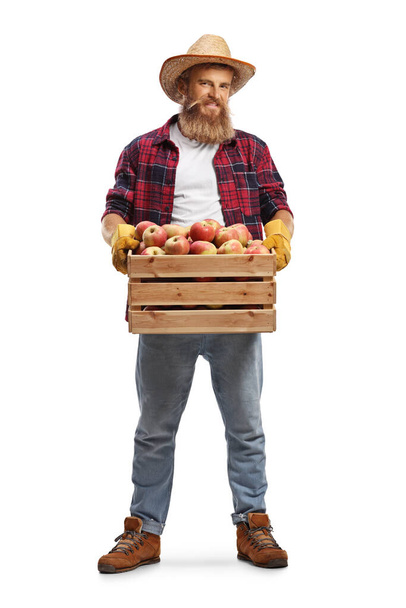 Full length portrait of a farmer with a crate full of fresh apples isolated on white background - Фото, изображение