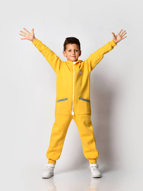 Boy in yellow warm jumpsuit showing victory gesture - Fotó, kép