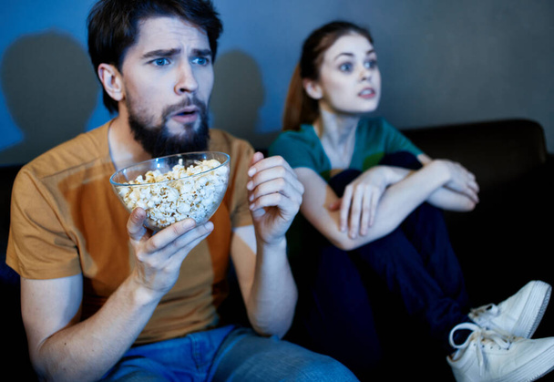 Un hombre y una mujer están viendo la televisión por la noche en el interior - Foto, Imagen