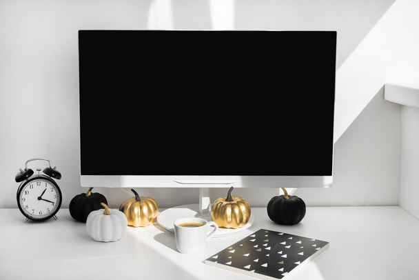 Desktop-Computer mit leerem Bildschirm in einem modernen minimalistischen Büroraum mit herbstlicher Dekoration. Papierboxen in einem Trolley auf dem Schreibtisch. Online-Shopping-Konzept - Foto, Bild