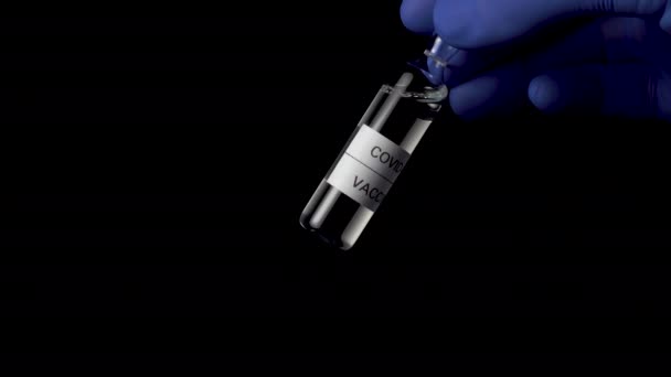 Πρωτότυπο εμβολίου του ιού του κερατοειδούς, COVID-19. Φύσημα με σύνθεση ένεσης closeup στο χέρι ενός ερευνητή με μπλε ιατρικά γάντια σε μαύρο φόντο - Πλάνα, βίντεο