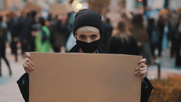 Proteste und Demonstrationen. Rebellische Frau mit Gesichtsmaske fällt auf  - Foto, Bild