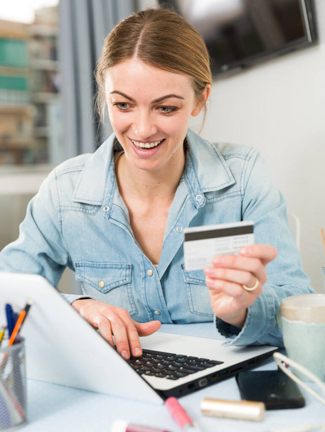 Girl buying online with laptop and credit card at home - Foto, imagen