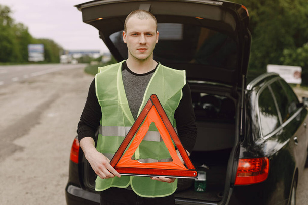 Αυτοκίνητο με προβλήματα και ένα κόκκινο τρίγωνο για να προειδοποιήσει τους άλλους χρήστες του δρόμου - Φωτογραφία, εικόνα