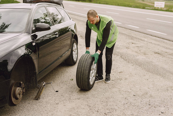 Man changing broken wheel on car - Fotó, kép