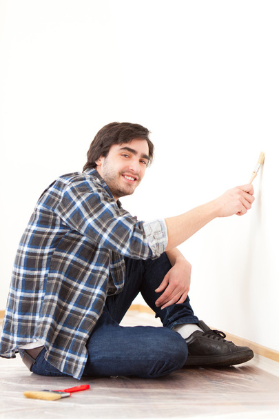 Attractive young man painting a wall in his new flat - Zdjęcie, obraz