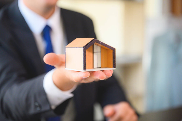 Инвестиции в недвижимость и финансовая концепция ипотечного жилищного кредитования. Бизнесмен показывает домашнюю модель - Фото, изображение