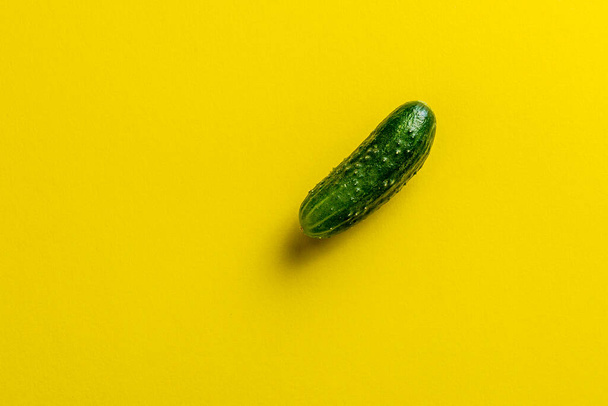 green cucumber isolated over the yellow background top view - Фото, изображение