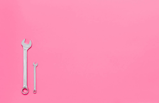 Two metal wrenches of different sizes isolated on pink background with copy space. Conceptual idea of the differences between: boss and employee, older and younger, big and small, parent and child. - Foto, afbeelding