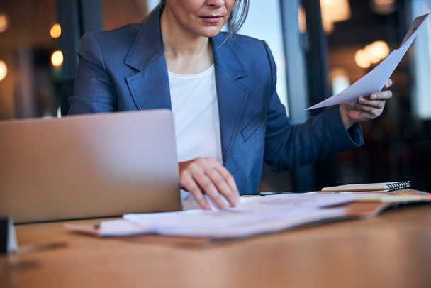 Элегантная деловая женщина изучает документы в офисе - Фото, изображение