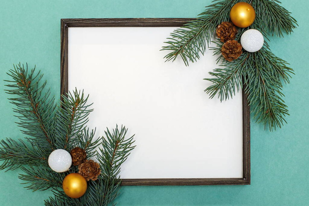 Christmas composition of fir branches, pine cones, Christmas toys and decorations. Christmas frame with space for text on a light green background - Fotó, kép