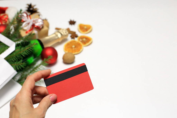 Christmas shopping concept. Hand with a credit card, a bag of groceries, champagne and gifts on a white background. Online shopping, credit card paymen - Photo, Image
