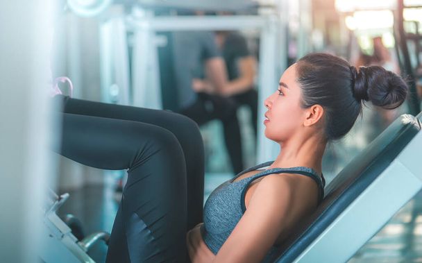 Asiatique femme fait jambe presse dans fitness gymnase en salle de sport train salle de gym. - Photo, image