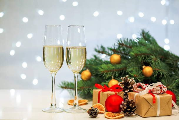 Dois copos de composição de champanhe com decorações de Natal e Ano Novo em um fundo embaçado de guirlandas ardentes - Foto, Imagem