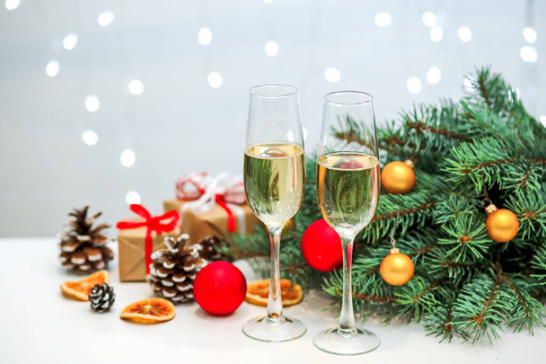 Two glasses of champagne composition with Christmas and new year decorations on a blurry background of burning garlands - Valokuva, kuva