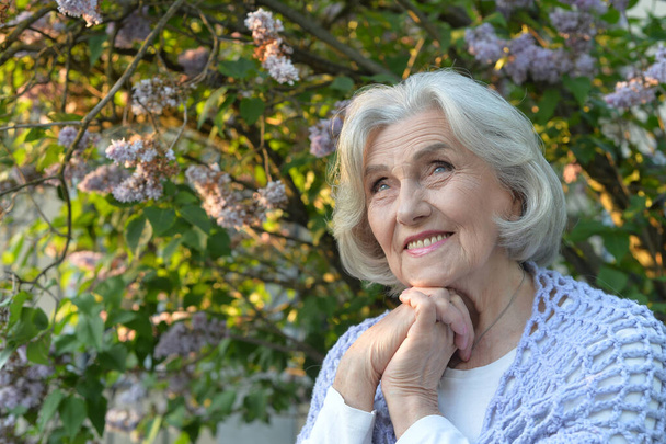  senior beautiful  happy woman posing by  lilacs in   park - Photo, image